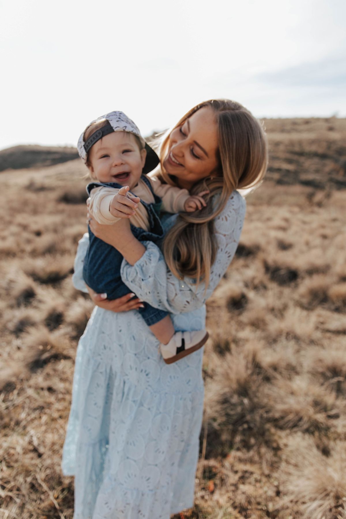 A mother holding her baby in a sunlit field